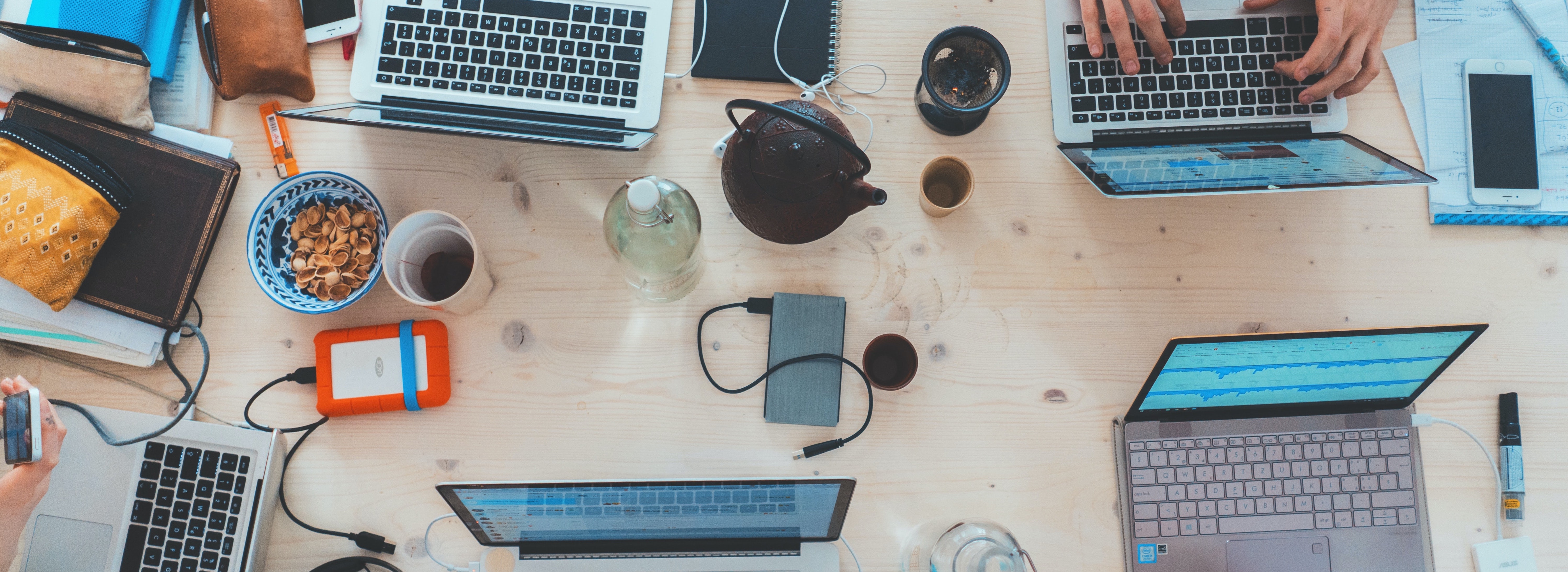 A stock photo depicting a group of laptops around a messy coffee shop table.